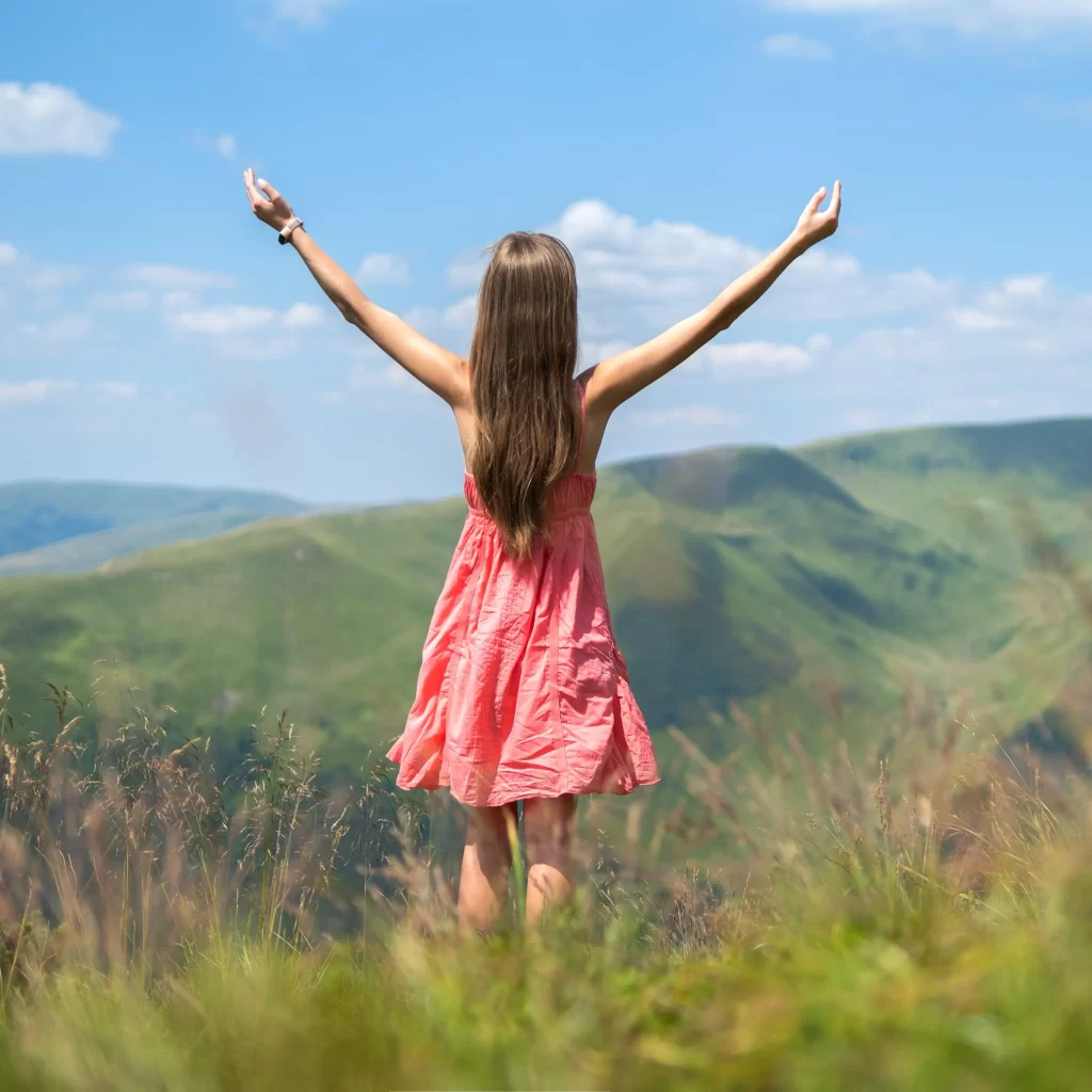 young-woman-in-red-dress-standing-on-grassy-meadow