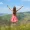 young-woman-in-red-dress-standing-on-grassy-meadow