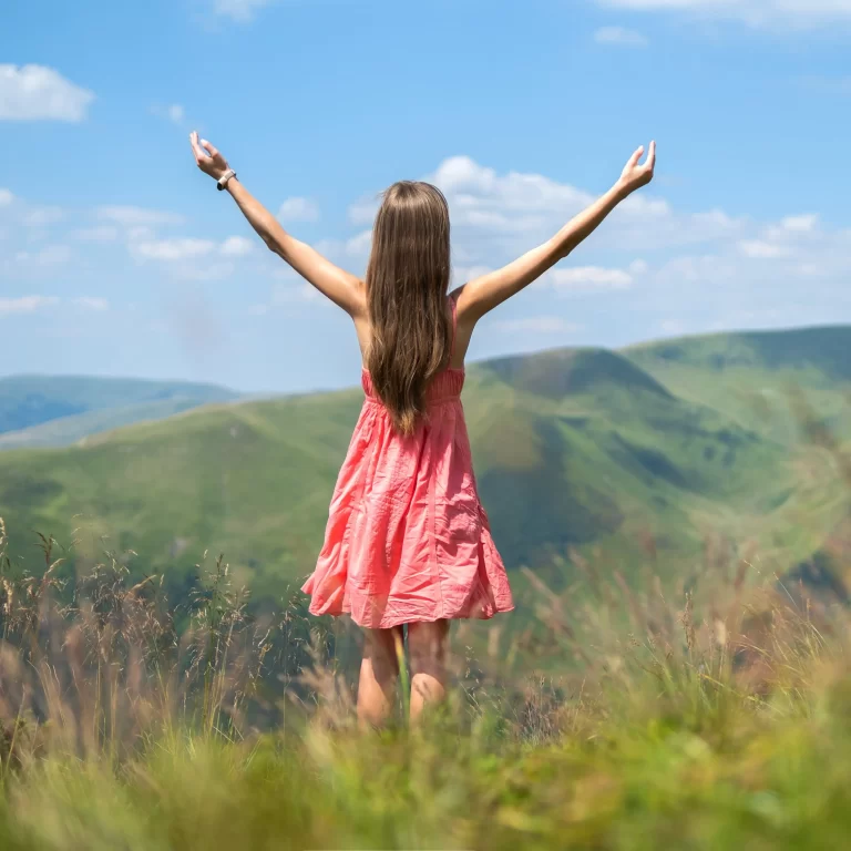 young-woman-in-red-dress-standing-on-grassy-meadow